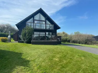 a large black house with glass windows on a lawn at Willow at Retallack Resort in Saint Columb Major
