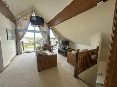 a living room with a large window and a couch at Willow at Retallack Resort in Saint Columb Major