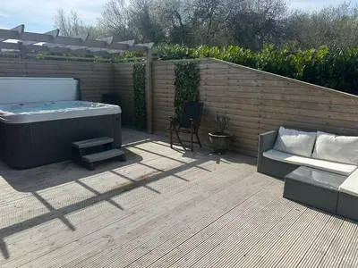 a patio with a hot tub and a couch and a chair at Willow at Retallack Resort in Saint Columb Major