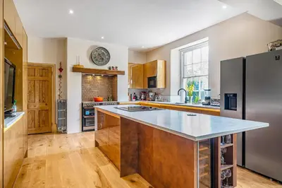 a kitchen with a stainless steel refrigerator and wooden floors at The Old Vicarage in Truro