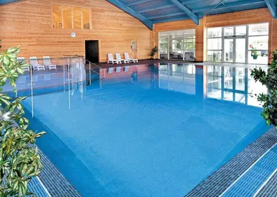 a large swimming pool with blue water in a building at Atlantic Lodge - 4 Bedroom - Pool -Spa - Gym in Newquay