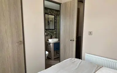 a bedroom with a bathroom with a sink and a mirror at Vyvyenne Lodge in Padstow