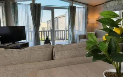 a living room with a couch and a television at Vyvyenne Lodge in Padstow