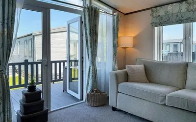 a living room with a couch and a balcony at Vyvyenne Lodge in Padstow