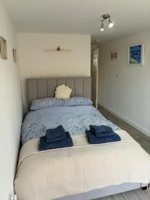 a bedroom with a bed with two blue towels on it at Park Rd in Redruth