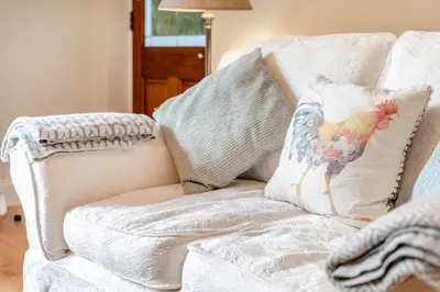 a white couch with a chicken pillow on it at 1 Bed in Fowey oc-p33360 in Fowey