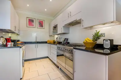 a large kitchen with white cabinets and appliances at 3 Bed in Fowey oc-o33078 in Fowey