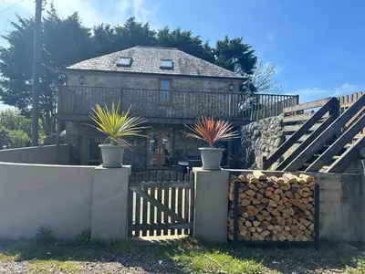 a house with potted plants in front of a fence at The Mowhay tranquil farm stay with views in Redruth