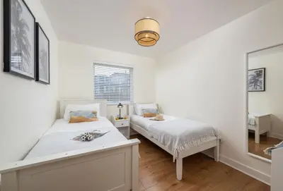 a bedroom with two beds and a mirror at 12 Ocean One in Newquay