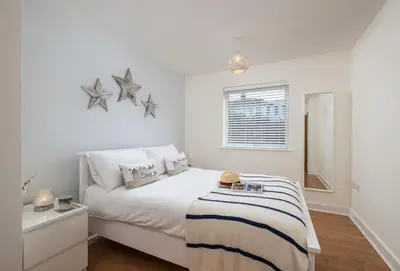 a white bedroom with a bed with stars on the wall at 12 Ocean One in Newquay