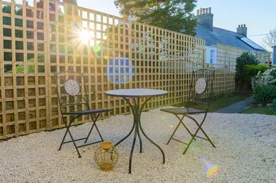 two chairs and a table in a yard with a fence at Danny Cottage in Saint Dennis