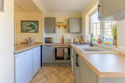 a kitchen with white cabinets and a sink at Danny Cottage in Saint Dennis