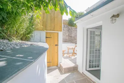 a white house with a door and a patio at Doolittle in Porthleven