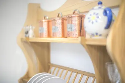 a wooden shelf with jars and vases on it at Doolittle in Porthleven