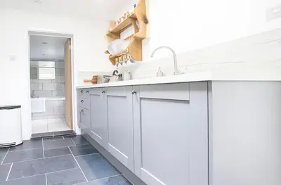 a kitchen with white cabinets and a sink at Doolittle in Porthleven