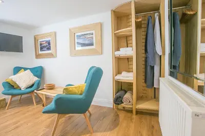 a living room with two blue chairs and a table at Doolittle in Porthleven