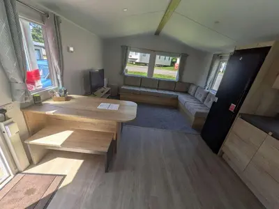 a living room with a table and a couch in a van at Willows Way Parkdean Newquay in Porth