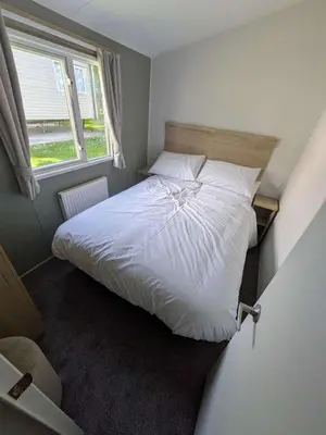 a bedroom with a white bed with a window at Willows Way Parkdean Newquay in Porth