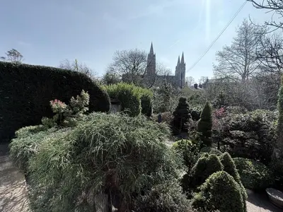 a garden with bushes and a church in the background at Tamarin in Truro