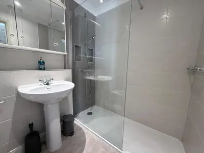 a white bathroom with a sink and a shower at Tamarin in Truro