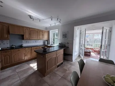 a large kitchen with wooden cabinets and a table at Tamarin in Truro