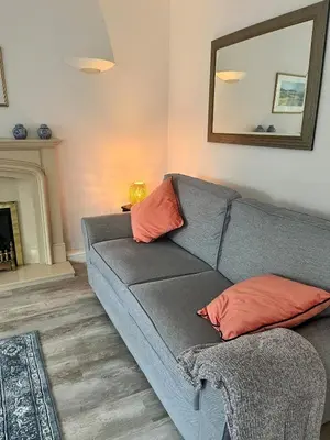 a living room with a gray couch with orange pillows at Tamarin in Truro