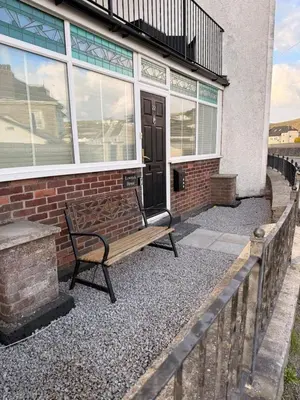 a bench in front of a brick building with a door at Lowenek House in Perranporth