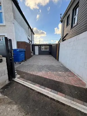 a garage with a brick driveway next to a building at Lowenek House in Perranporth