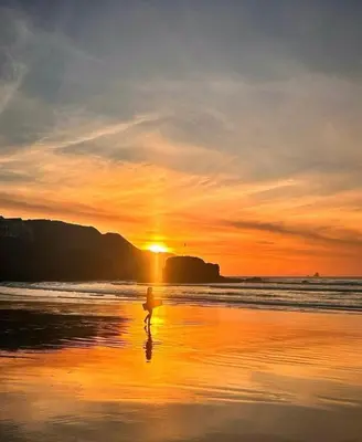 a person walking on the beach at sunset at Lowenek House in Perranporth
