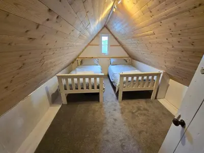 a room with two beds in a small attic at Lowenek House in Perranporth