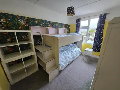 a childs bedroom with a bunk bed and shelves at Lowenek House in Perranporth