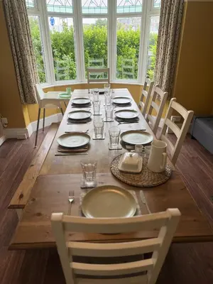 a dining room table with plates and glasses on it at Lowenek House in Perranporth