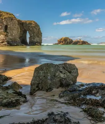 a beach with a rock formation in the water at Lowenek House in Perranporth