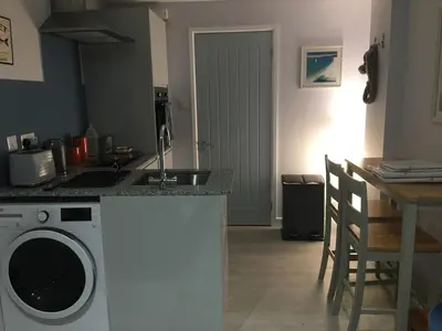 a kitchen with a washing machine next to a table at The Lodge in Truro