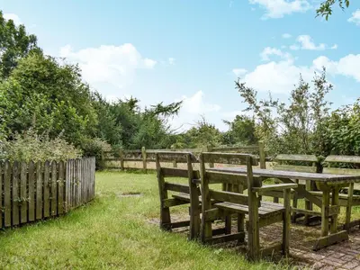 a wooden picnic table with two benches in the grass at Nutmeg's - Uk50373 in Camelford