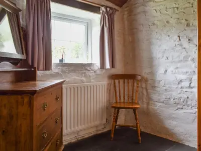 a wooden chair in a room with a window at Skyber - Uk50374 in Camelford
