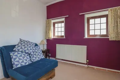 a living room with a blue chair and purple wall at The Loft in Truro