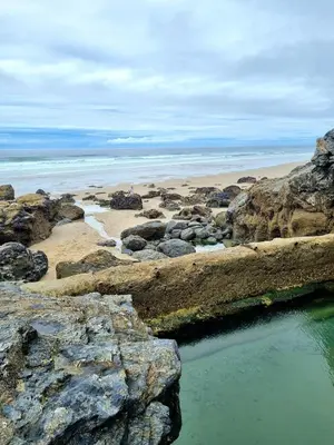 a beach with rocks and a body of water at Towan Valley, Porthtowan - Coastal 3 Bedroom Eco-Home with Hot Tub in Truro