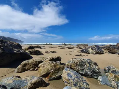 a beach with rocks on the sand and the ocean at Towan Valley, Porthtowan - Coastal 3 Bedroom Eco-Home with Hot Tub in Truro