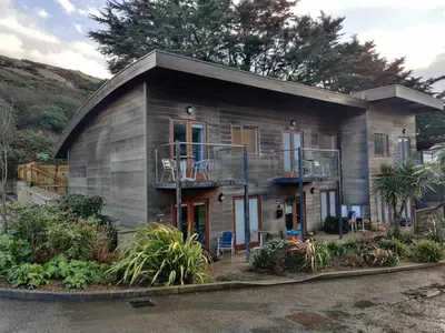 a small house with a balcony on the side of it at Towan Valley, Porthtowan - Coastal 3 Bedroom Eco-Home with Hot Tub in Truro