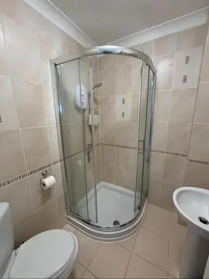 a bathroom with a shower with a toilet and a sink at Pirans Apartments in Perranporth