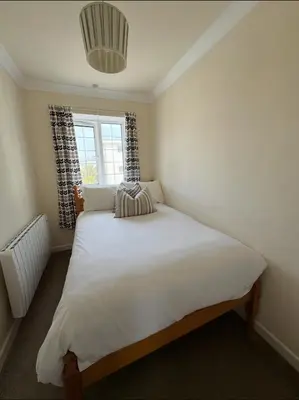 a bedroom with a large white bed with a window at Pirans Apartments in Perranporth