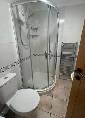 a bathroom with a toilet and a glass shower at Pirans Apartments in Perranporth