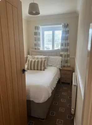a small bedroom with a bed and a window at Pirans Apartments in Perranporth