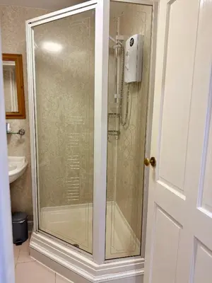 a shower with a glass door in a bathroom at Pirans Apartments in Perranporth