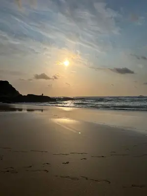 a sunset on a beach with the ocean at L20 at Seven Bays Park in St Merryn
