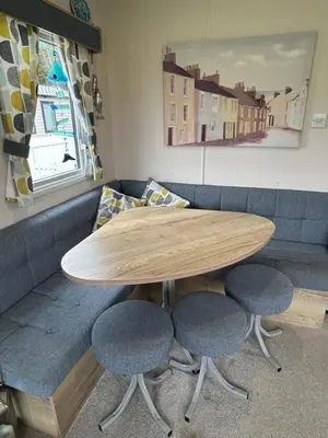 a wooden table with two chairs and a couch at L20 at Seven Bays Park in St Merryn