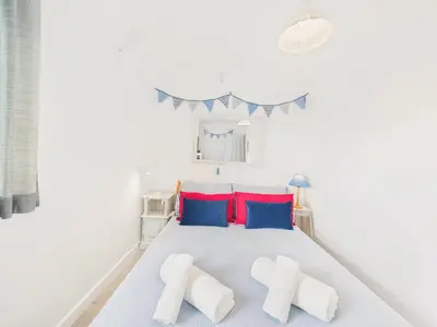 a white bedroom with a bed with blue and red pillows at Seaside 2-bed Home in Flushing with Free Parking & sea views in Falmouth