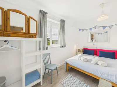 a bedroom with a bed and a chair at Seaside 2-bed Home in Flushing with Free Parking & sea views in Falmouth