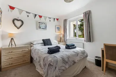 a bedroom with a bed and a dresser and a tv at Macalby Cottage in Padstow
